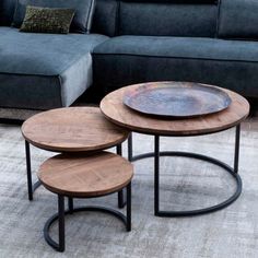 three wooden tables sitting on top of a carpeted floor next to a gray couch