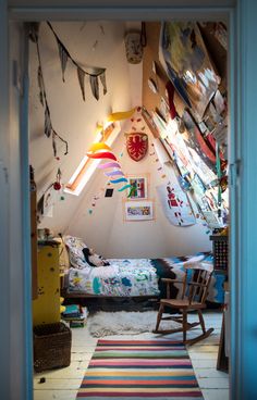 a room with a bed, rocking chair and colorful rug