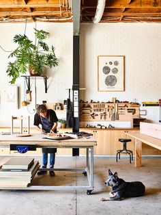 a man and his dog are working in an industrial style workshop with woodworking equipment