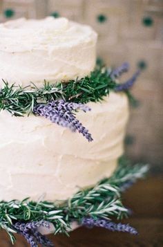 a close up of a cake on a table with lavenders and rosemary sprigs