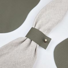 a close up of a tie on a white surface with grey leather straps and buttons