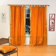 a living room with orange curtains and a chair in front of a window that has gold sequins on it