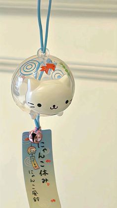 a cat ornament hanging from a blue string with writing on it and a tag attached