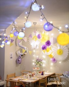 a dining room filled with lots of lights and flowers hanging from the ceiling next to a table