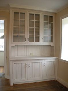 an empty room with white cabinets and wood floors in the corner, while no one is present