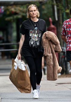 a woman walking down the street carrying shopping bags and a teddy bear coat on her back