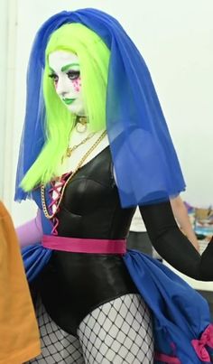 a woman with green hair and makeup is dressed in costume