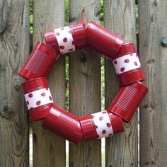 a red and white polka dot wreath on a wooden fence next to a wood fence