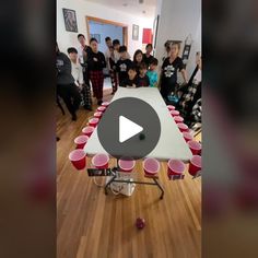 a group of people standing around a table with red cups on it and one person holding a video game controller