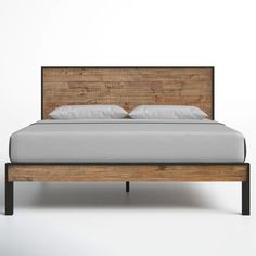 a wooden bed frame with white sheets and pillows