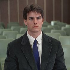 a man wearing a suit and tie in front of rows of green chairs