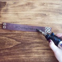 a person is holding a pen and writing on a piece of leather that says, dremel maker