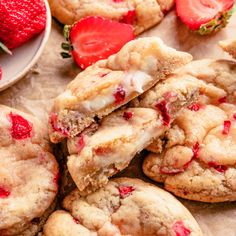 three strawberry cookies with white chocolate chips and strawberries on a plate next to each other