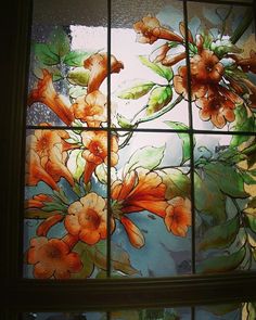 a stained glass window with orange flowers in the center and green leaves on the outside