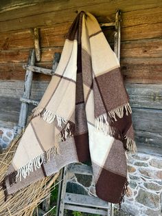 a brown and white checkered blanket hanging on a wall next to an old wooden ladder