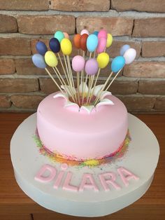 there is a pink cake with many balloons on it and the word diara spelled out