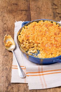 macaroni and cheese is in a blue dish with a spoon on a napkin