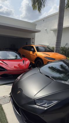 two exotic sports cars parked in front of a house with palm trees on the driveway