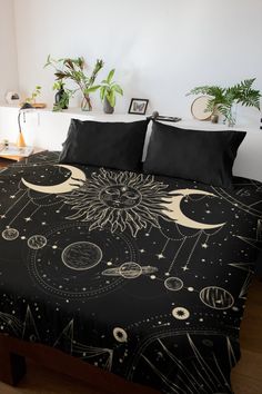 a bed covered in black and white bedspread with sun, moon and planets on it