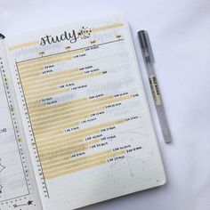 an open notebook with some writing on it and a pen next to it, sitting on a white surface