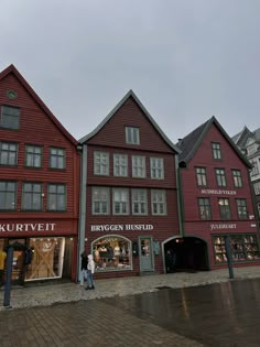 people are walking around in front of some red buildings on a cobblestone street