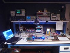 a desk with several electronic equipment on it and a laptop computer sitting on top of it