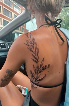 a woman with tattoos on her back sitting in a car