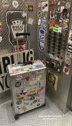 a piece of luggage sitting in front of a metal wall with stickers on it