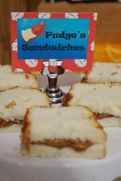 some sandwiches are on a white plate with a sign that says fudge's sandwiches