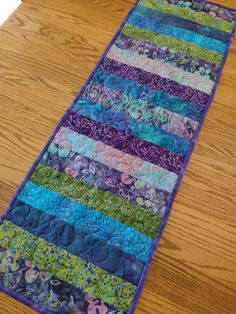 a quilted table runner on top of a wooden table