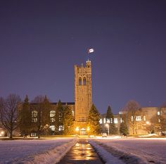 a clock tower lit up at night with snow on the ground