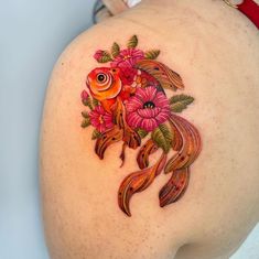 a woman's thigh with a fish and flowers tattoo on it