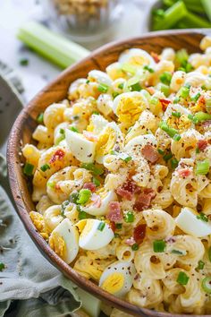 a bowl filled with macaroni salad on top of a table next to celery