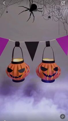 two halloween lanterns hanging from a string with spider webs on it and purple flags