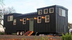 a black tiny house sitting on top of a dirt field