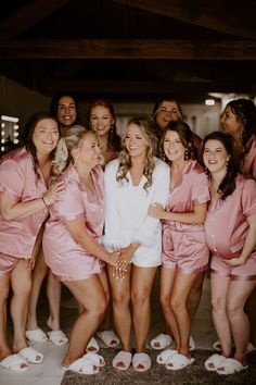 a group of women standing next to each other wearing pink robes and slippers on their feet