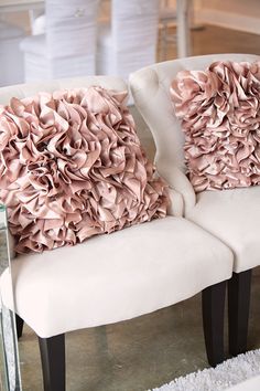 two white chairs with pink pillows on them