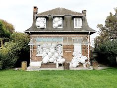 a house with balloons attached to the windows and in front of it, on grass