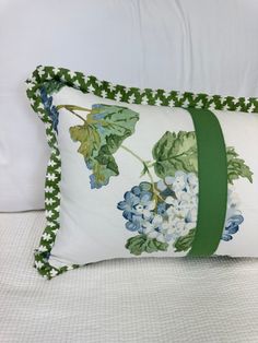 a white pillow with blue and green flowers on it sitting on top of a bed