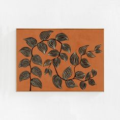 a painting with leaves on it hanging on a wall