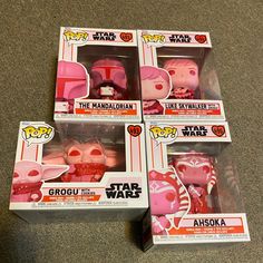 five star wars action figures in boxes on the floor, with one pink and one red