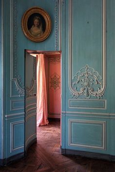 an open doorway leading to a room with blue walls and wood floors, painted in pale colors