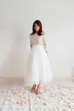 a woman in a white dress standing on a bed of rose petals with her hands behind her back