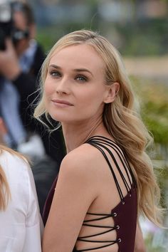 a woman with long blonde hair wearing a black and white dress standing in front of photographers