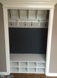 an empty room with white shelves and hooks