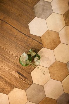 a vase with flowers sitting on the floor next to a wooden table and chair top