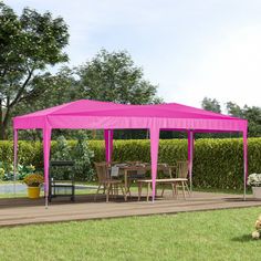 a large pink tent sitting on top of a lush green field next to a picnic table