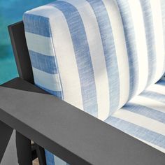 a close up view of a blue and white striped couch near the water's edge