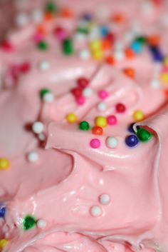 a close up view of a pink cake with sprinkles and candy on it