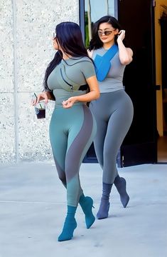 two women walking down the street in matching leggings and high heeled boots